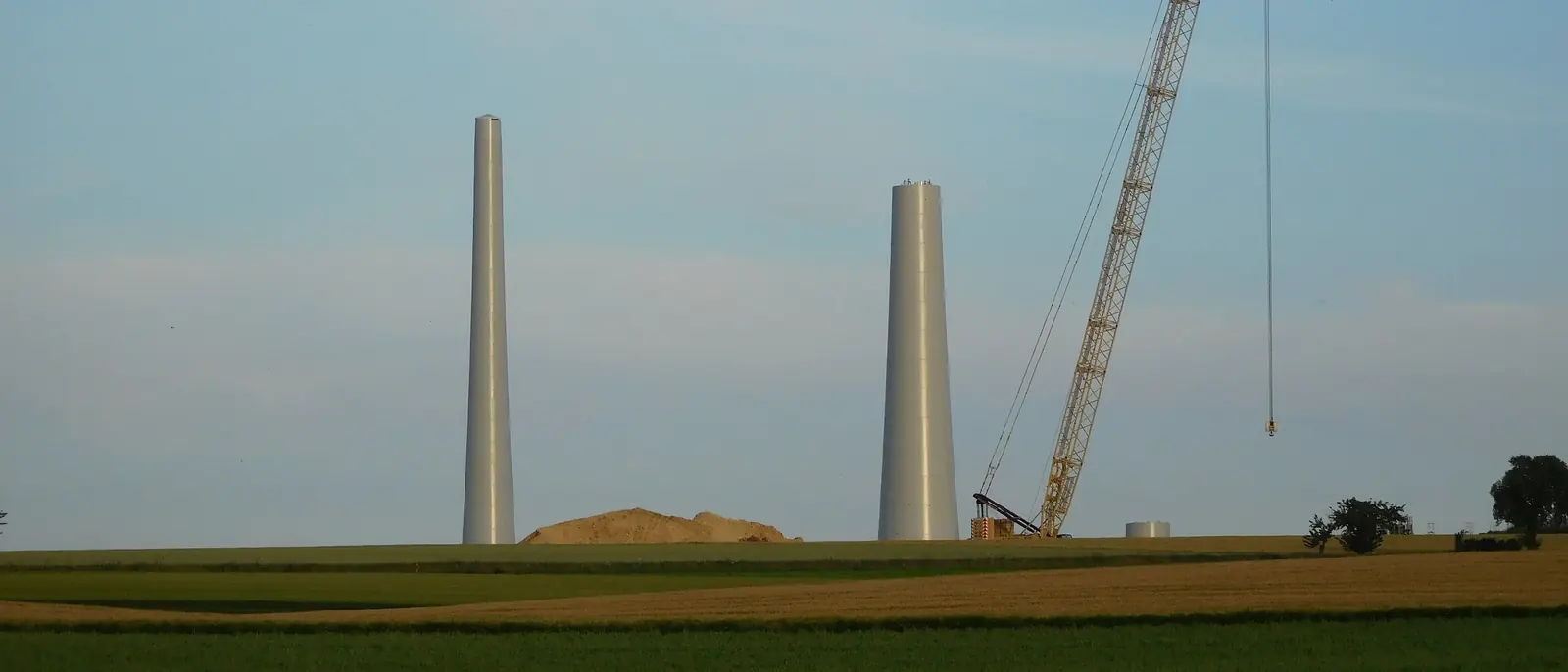 Torres de aerogenerador en montaje junto a una grúa, en campo abierto