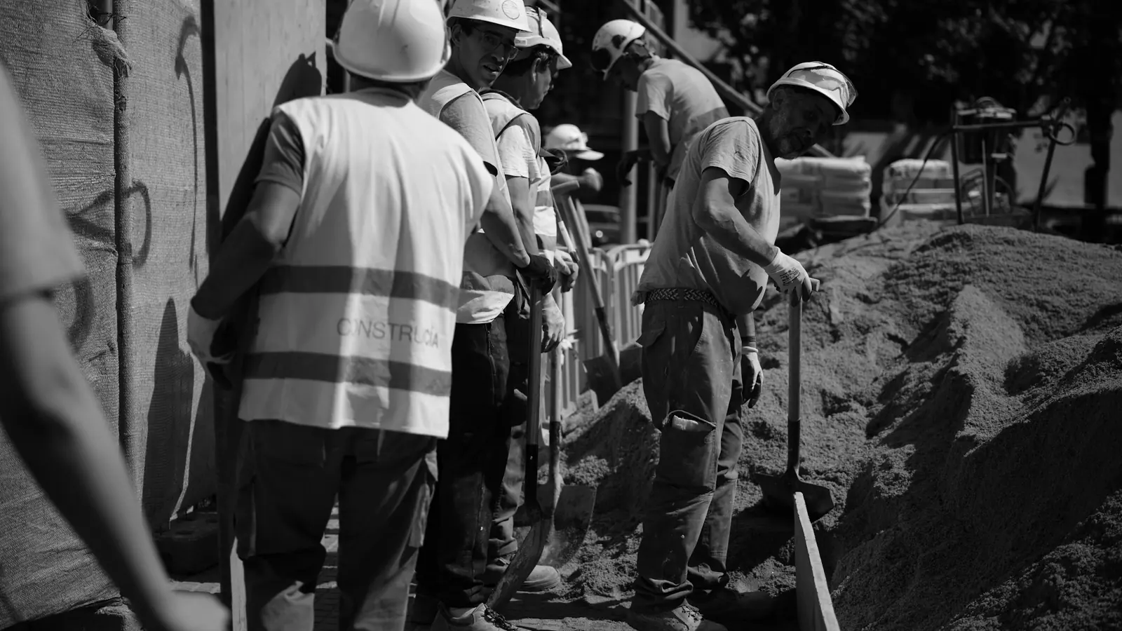 Cuadrilla con casco y chaleco trabajando en una zanja