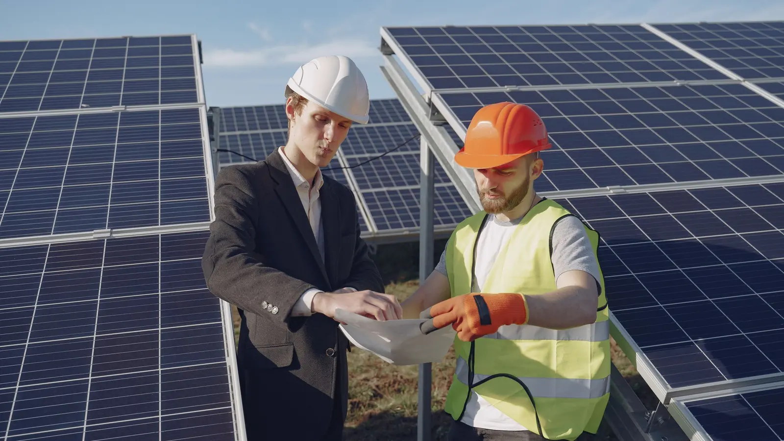 Dos responsables con casco revisan documentación entre filas de paneles solares