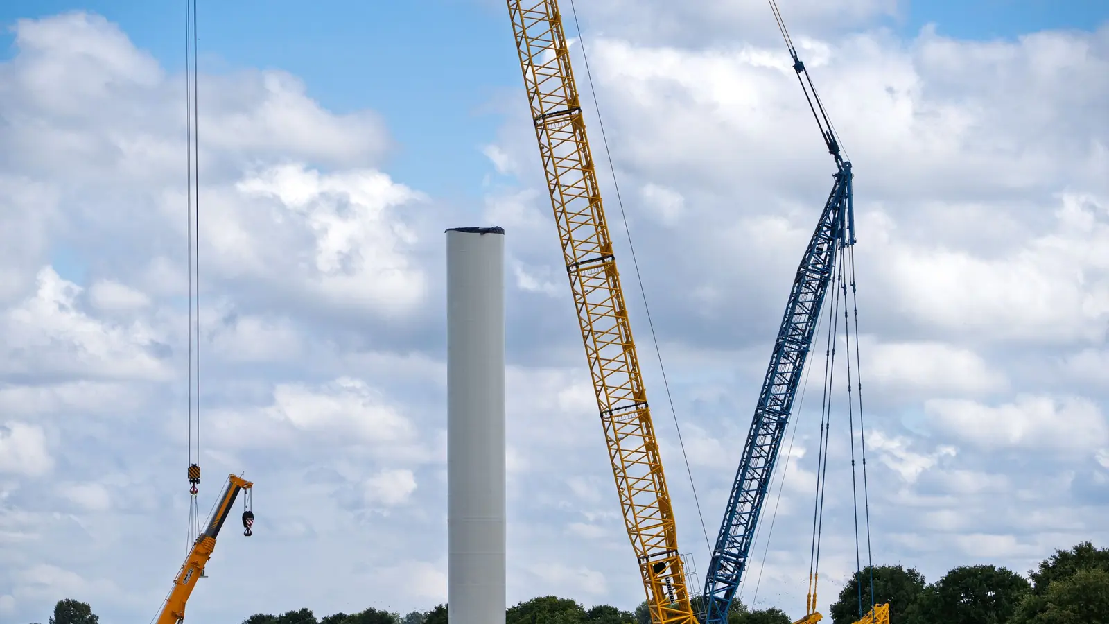 Grúas montando la torre de un aerogenerador bajo un cielo cubierto